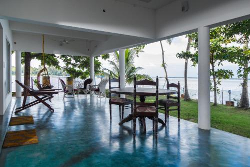 a dining room with a table and chairs and the ocean at Orchid Lake View Homestay in Alleppey