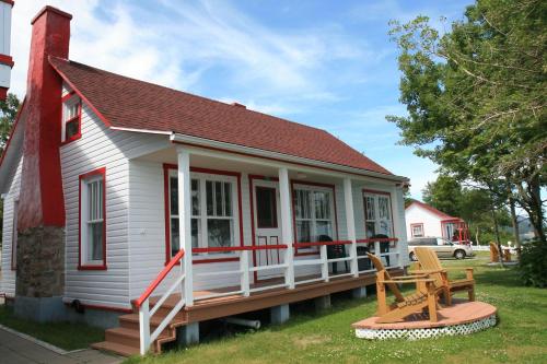 a small white house with a porch and a bench at Motel et Chalets Bo-Fleuve Evangeline in Saint-Siméon