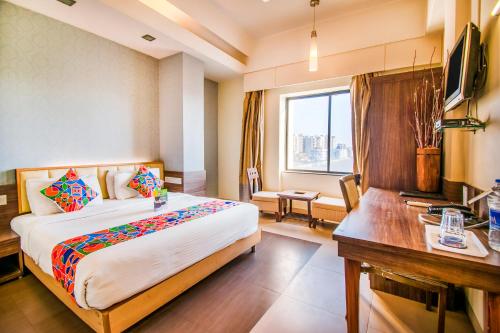 a hotel room with a bed and a desk and a window at Hotel Sadanand Regency in Pune