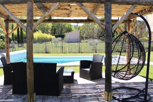 een patio met 2 stoelen en een schommel naast een zwembad bij Bastide de Fanny in Rognes