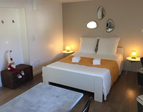 um quarto com uma grande cama branca e duas lâmpadas em La pierre du petit'hom em Goxwiller