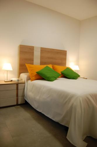a bedroom with a large bed with green and orange pillows at ALHAJAS DE CORDOBA in Córdoba
