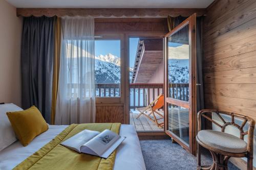a bedroom with a bed and a balcony with a mountain at Hotel Les Arolles in Méribel