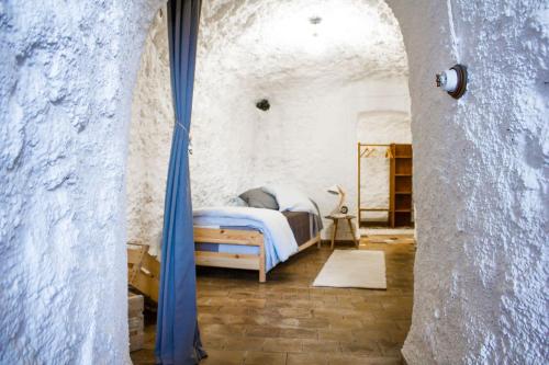 1 dormitorio con 1 cama en una pared de piedra en Cueva de Lindaraja, en Granada