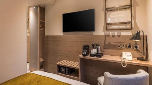 a hotel room with a desk with a tv and a bed at Sloane Place in London