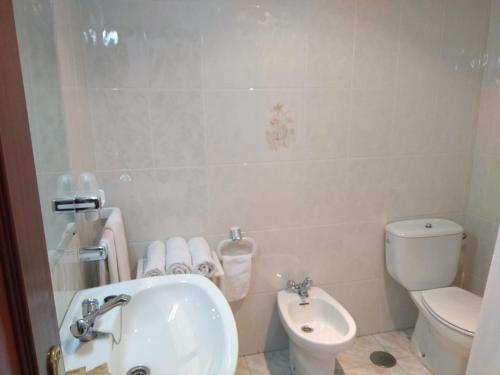 a bathroom with a white toilet and a sink at Hostal Mourelos in O Grove