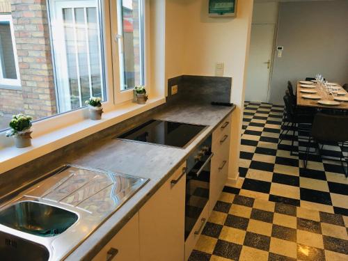 a kitchen with a sink and a checkered floor at 't Hoekske in Merkem