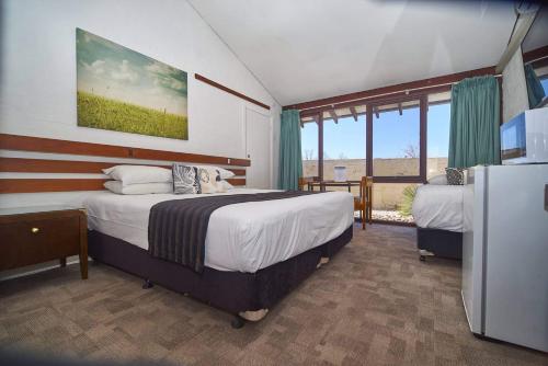 a bedroom with two beds and a large window at The Apple Inn in Batlow