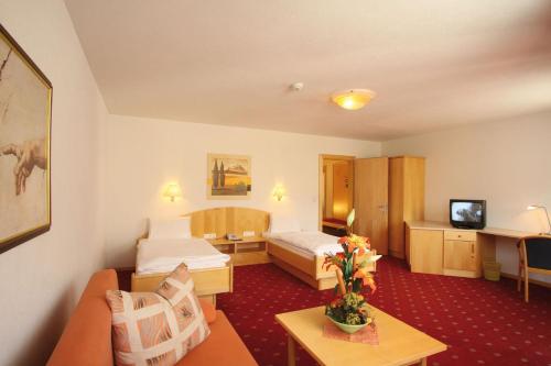 a hotel room with two beds and a couch at Aktiv-Hotel Traube am Mieminger Sonnenplateau in Wildermieming