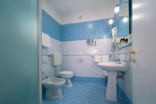a blue and white bathroom with a toilet and a sink at CDH Hotel Modena in Modena