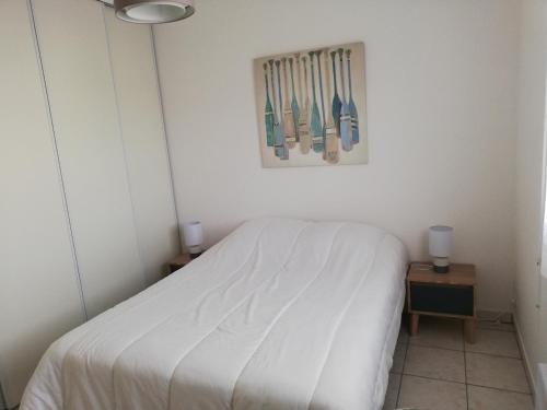 une chambre avec un lit blanc et un tableau au mur dans l'établissement Appartement la Rochelle, à Aytré