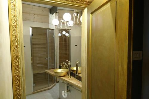 uma casa de banho com um espelho de ouro e um lavatório em Ugo Architect's Lodge Classic em Bolzano