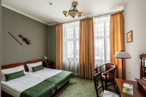 a bedroom with a bed and a desk and window at Villa Elise Park Pension in Stronie Śląskie