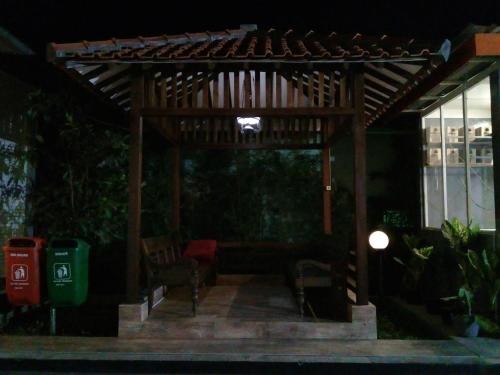 a wooden pergola with a couch and chairs under it at Wisma Lovebird in Kalianget
