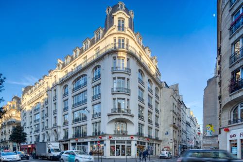 un grand bâtiment blanc dans une rue de la ville avec des voitures dans l'établissement Gravilliers, à Paris