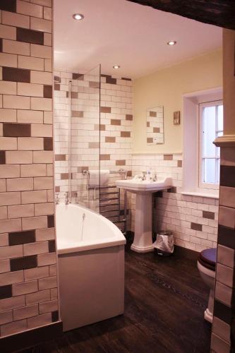 a bathroom with a bath tub and a sink at Red Lion Coaching Inn in Ellesmere