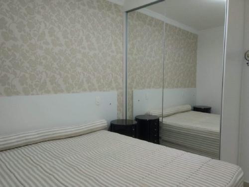 sypialnia z 2 łóżkami i lustrem na ścianie w obiekcie Apartamento Praia Grande 301 w mieście Ubatuba