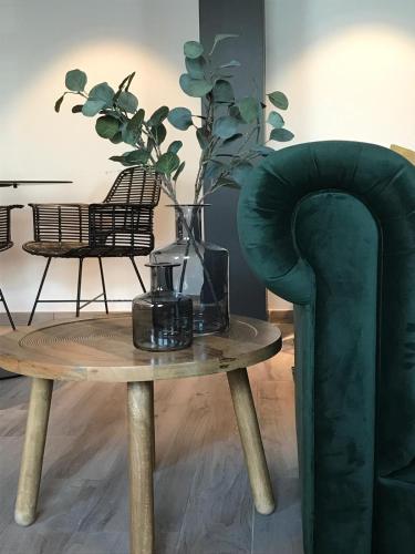 a green chair and a table with a vase on it at Hotel La Passerelle in Grandhan