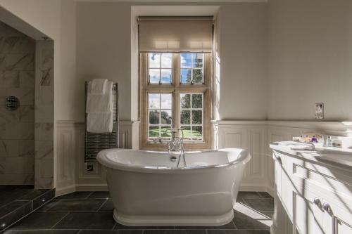 a white bath tub in a bathroom with a window at Tylney Hall Hotel in Hook