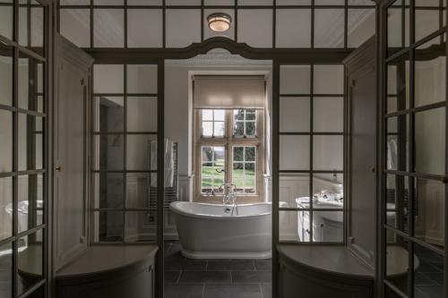 La salle de bains est pourvue d'une baignoire et d'une fenêtre. dans l'établissement Tylney Hall Hotel, à Hook
