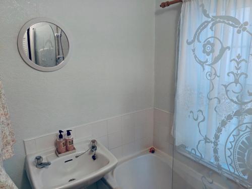 a bathroom with a sink and a bath tub at Little Mermaid Cottage in Dawlish