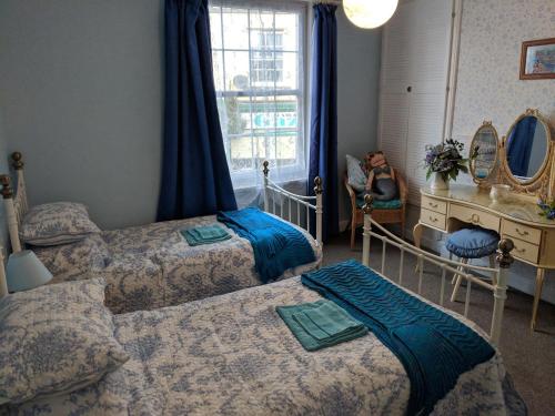 a bedroom with two beds and a woman sitting in a chair at Little Mermaid Cottage in Dawlish