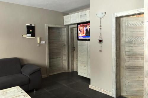 a living room with a couch and a tv on a wall at Apartmán Luky in Vyšné Ružbachy