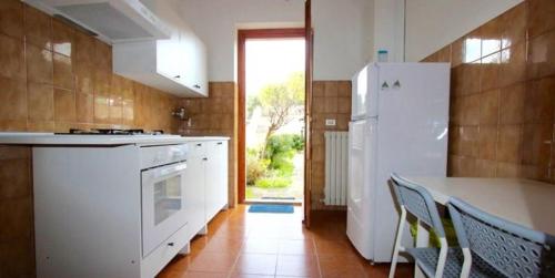 a kitchen with a white refrigerator and a table and chairs at N194 - Numana, ampio trilocale con giardino in Numana