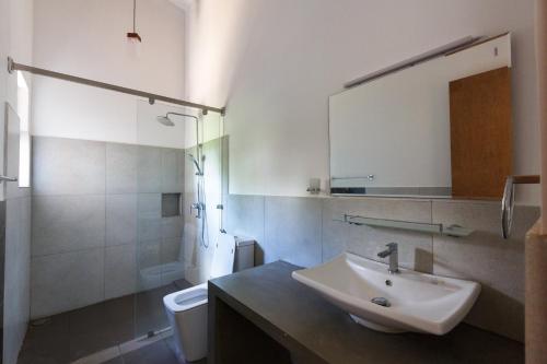 La salle de bains est pourvue d'un lavabo, de toilettes et d'un miroir. dans l'établissement Blue Sands Beach Resort, à Pasikuda