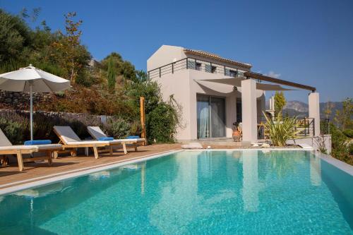 a swimming pool with chairs and a house at Anemos Luxury Villas in Vasiliki