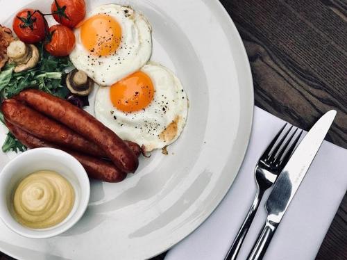 a plate of eggs and sausages on a table at Hotel Rezydencja Solei in Poznań