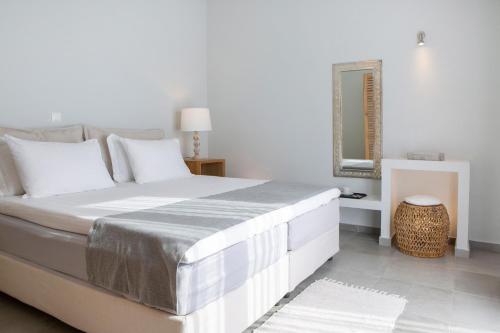 a white bedroom with a large bed with a mirror at Anemos Luxury Villas in Vasiliki