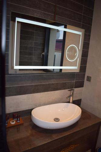 ein Badezimmer mit einem weißen Waschbecken und einem Spiegel in der Unterkunft Paris Luxury Guest House - CDG Aéroport in Roissy-en-France