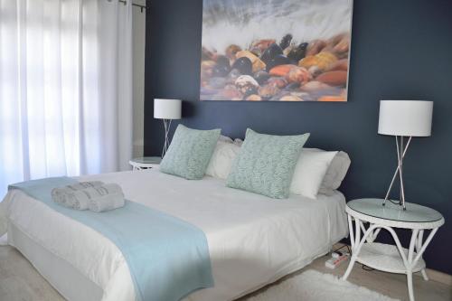 a bedroom with a white bed with a painting on the wall at Molensicht No. 8 in Swakopmund