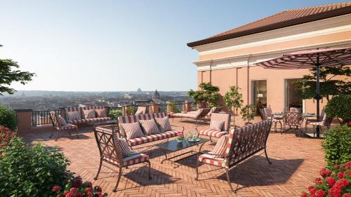 a patio with chairs and a table and an umbrella at Rocco Forte Hotel De La Ville in Rome