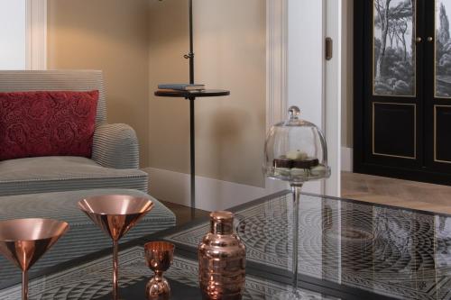 a living room with a glass table and a chair at Rocco Forte Hotel De La Ville in Rome
