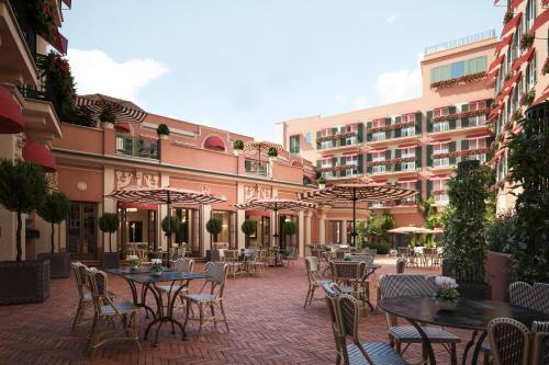 an outdoor patio with tables and chairs and a building at Rocco Forte Hotel De La Ville in Rome