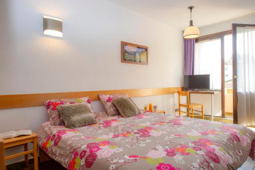 une chambre avec un lit avec une couette colorée dans l'établissement Residence Routes du Monde ATC Bagneres de Bigorre, à Bagnères-de-Bigorre