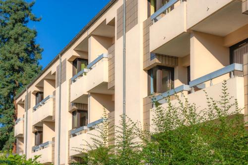 un immeuble d'appartements avec balcon et arbres dans l'établissement Residence Routes du Monde ATC Bagneres de Bigorre, à Bagnères-de-Bigorre