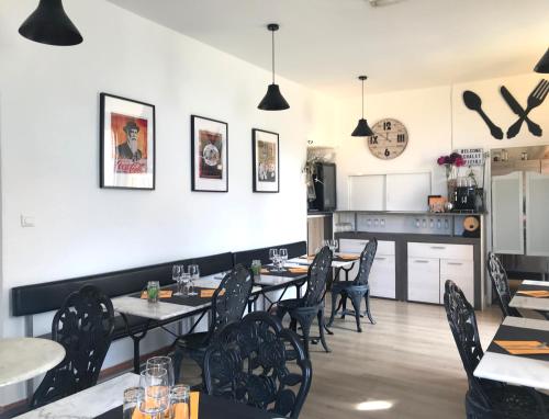 a dining room with tables and chairs and a kitchen at Gîte du Chalet Pietri in Olivese