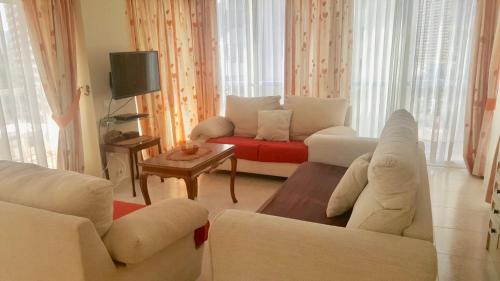 sala de estar con muebles blancos y sofá rojo en Apartamento El Rincon Benidorm, en Benidorm