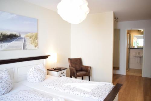 ein weißes Schlafzimmer mit einem Bett und einem Stuhl in der Unterkunft Villa Ocean Place in Haffkrug
