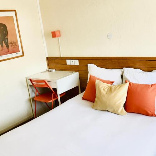 a bed with orange and white pillows and a table at Résidence Thibaud in Toulouse