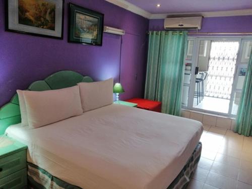 a bedroom with a large white bed with purple walls at Lenasia Guest Lodge in Lenasia
