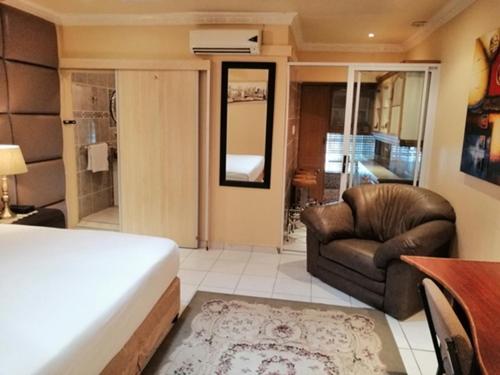 a bedroom with a bed and a couch and a chair at Lenasia Guest Lodge in Lenasia