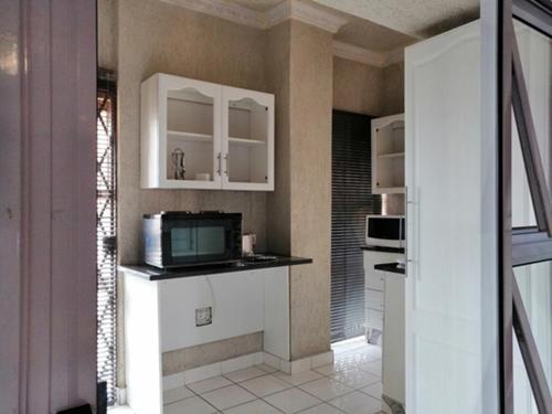 a kitchen with white cabinets and a microwave at Lenasia Guest Lodge in Lenasia