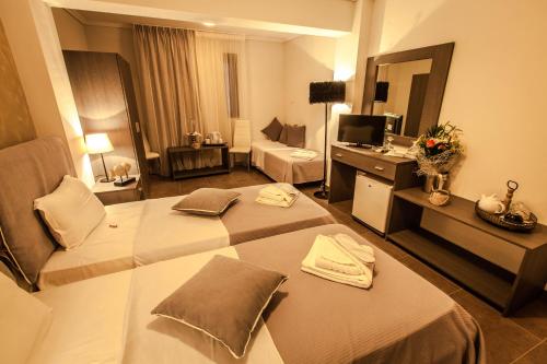 a hotel room with two beds and a television at Aqua Mare Sea Side Rooms in Nea Kalikratia