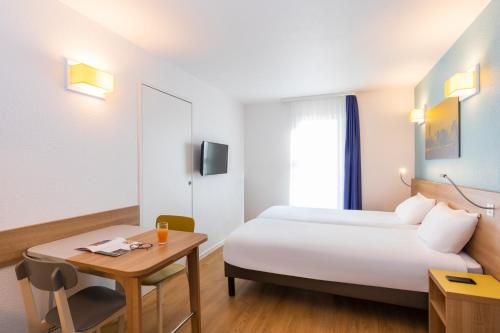 a hotel room with a bed and a table at Aparthotel Adagio Access La Défense - Place Charras in Courbevoie