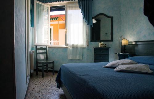 1 dormitorio con cama, ventana y silla en camere Caterina, en Bonassola
