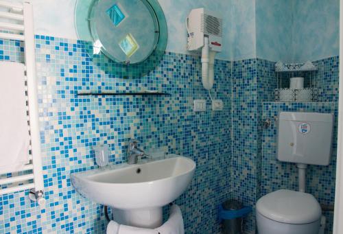 La salle de bains est pourvue de carrelage bleu, d'un lavabo et de toilettes. dans l'établissement camere Caterina, à Bonassola